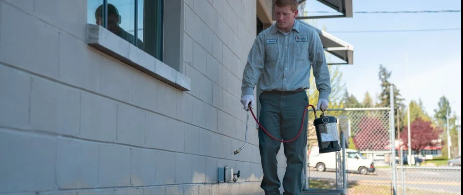 Worker treating the side of a building in Puyallup, WA, for pests.